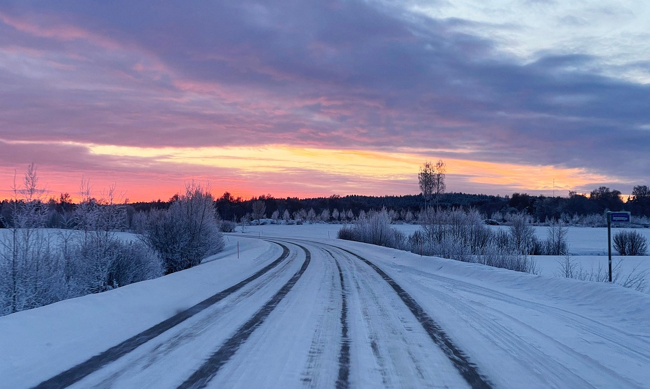 Route finlandaise enneigée bordée d'un arrêt de bus au coucher du soleil