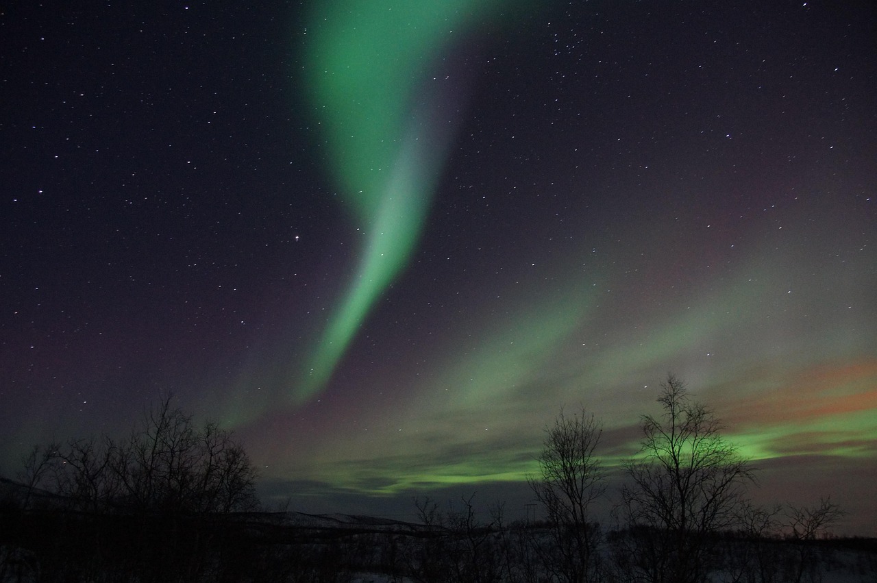 Arc d'aurore boréale verte au-dessus d'un paysage enneigé de Laponie