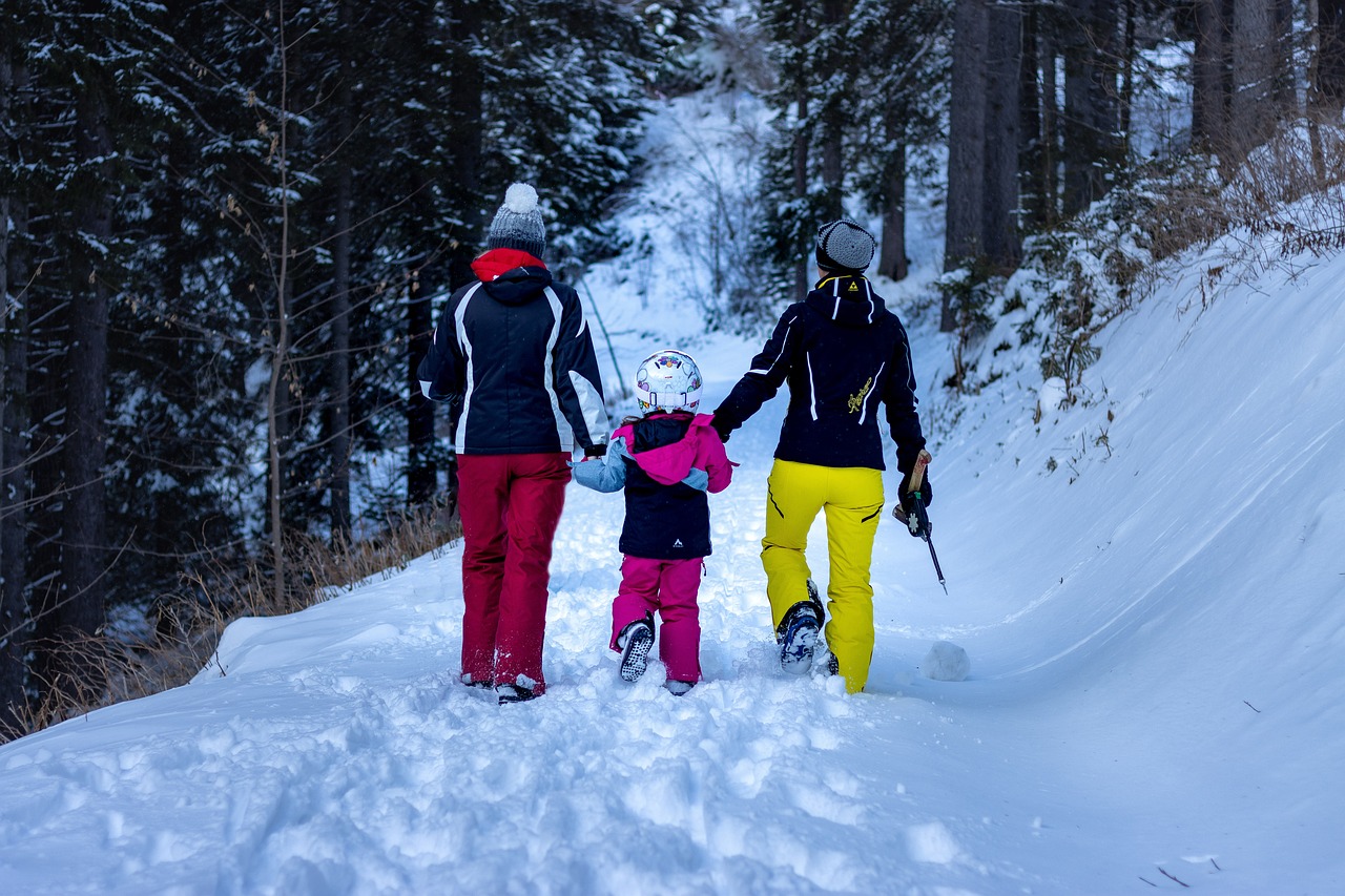 Family walking through a frost-covered forest in winter clothing