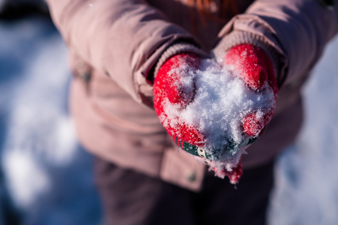 Child's hands in woollen mittens resting on the snow