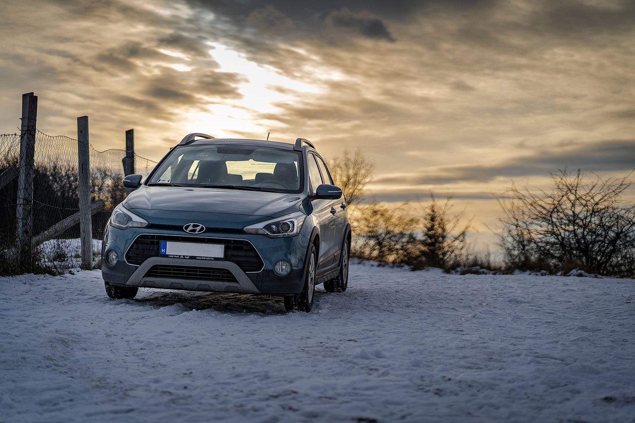 Cars parked under snow in a car park at the end of a winter day