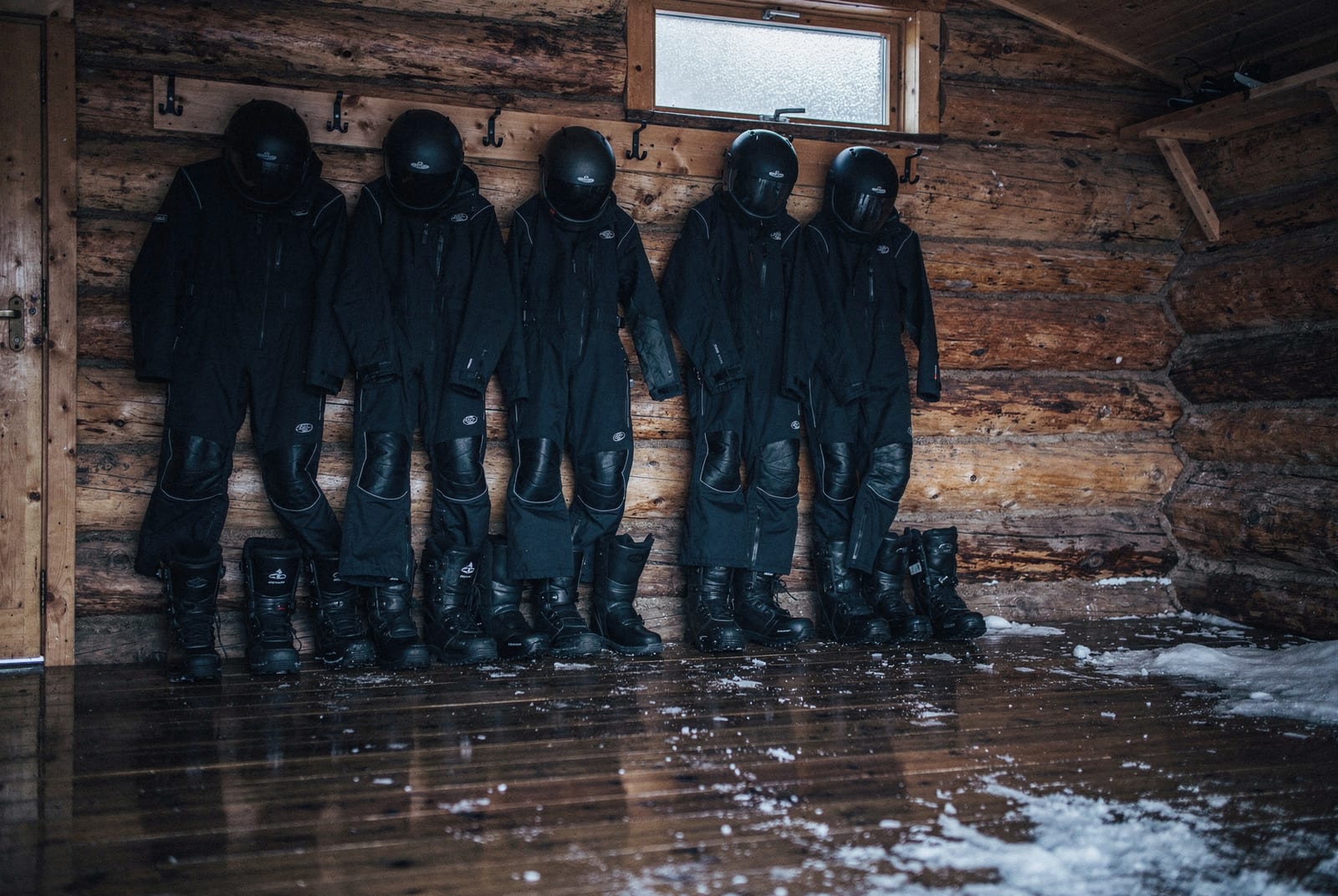 Combinaisons thermiques et casques de motoneige suspendus dans un vestiaire en bois en Laponie