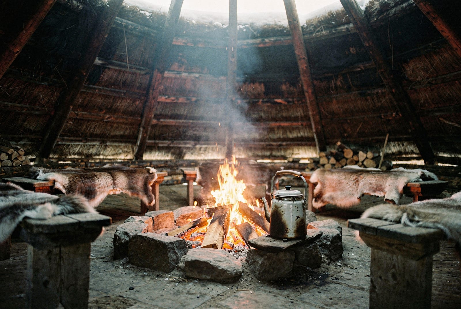 Inside a Lappish kota with an open fire in the central hearth and reindeer hides over the wooden benches