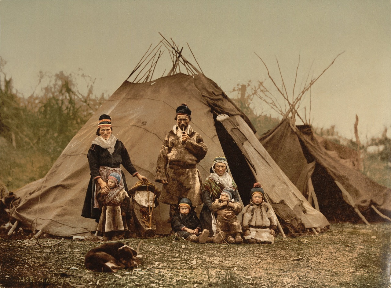 Photochrome de la fin du XIXe siècle montrant une famille samie devant deux tentes lávvu, image d'archive légendée à l'époque « Lappen Familie »