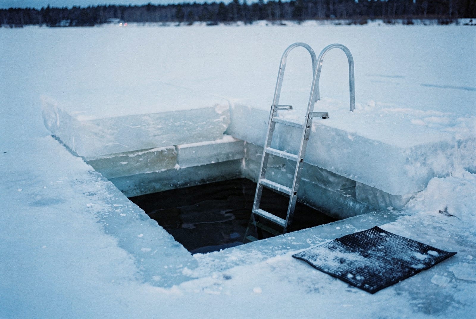 Trou carré découpé dans la glace d'un lac gelé de Laponie avec une échelle métallique pour le bain glacé